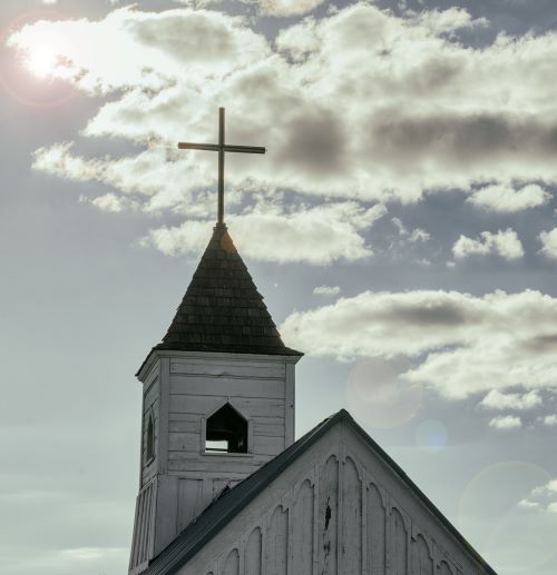 A church steeple with a cross reaching towards the sky